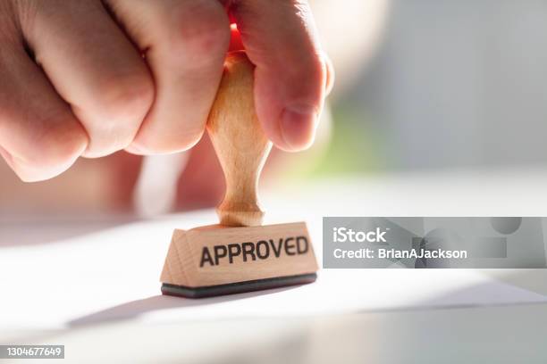 Businessman Stamping Approved Stamp On Document In Meeting Stock Photo - Download Image Now