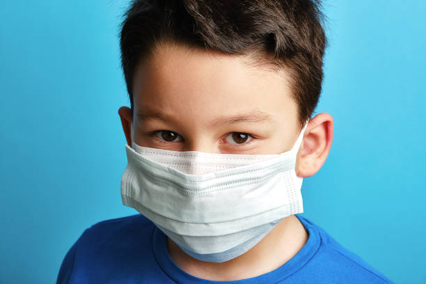 istock 8-9 years old cute child wearing double surgical mask 1304678104