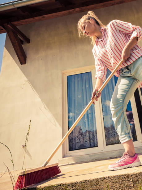 istock Woman cleaning patio using brush broom 1304679095