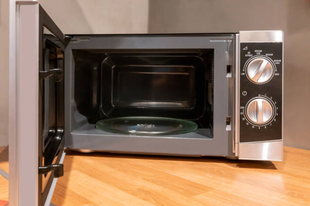 istock Door open microwave oven on wooden table in kitchen space. 1304679503