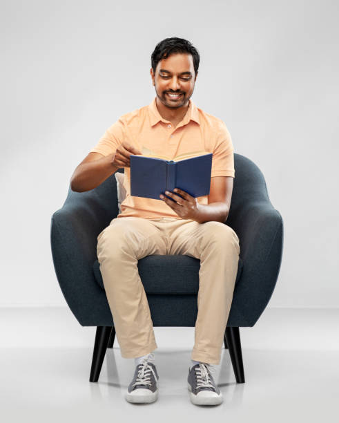istock happy young indian man reading book in chair 1304683103