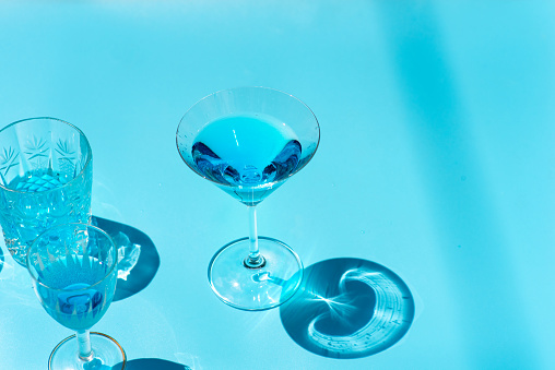 Blue cocktails alcoholic beverages in various glasses on blue background with strong shadows top view