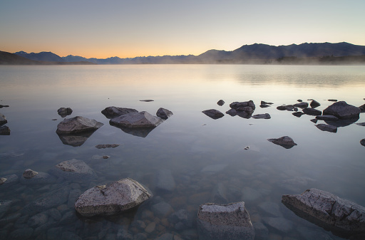 Pre-daswn light falls across the still waters of Lake Tekapo on New Zealand's South Island.