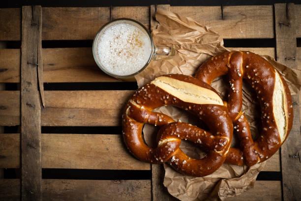 pretzels de pan alemán con cerveza en una mesa de madera - pretzel german culture food salt fotografías e imágenes de stock