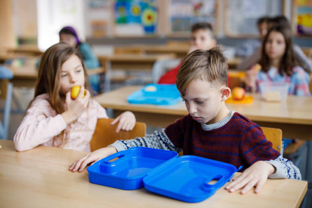 istock Unhappy boy looking at an empty launch box in the classroom 1304686380