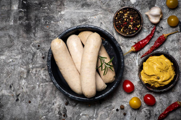 Raw Bavarian sausages with cooking ingredients on a plate Raw Bavarian sausages with cooking ingredients on a plate tabletop view bratwurst stock pictures, royalty-free photos & images