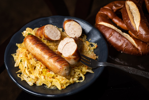 Bavarian fried sausages served with cooked sauerkraut sour cabbage on a plate tabletop view with food ingredients