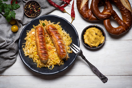 Bavarian fried sausages served with cooked sauerkraut sour cabbage on a plate tabletop view with food ingredients