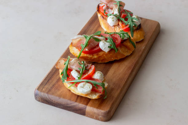 istock Bruschetta with ham, mozzarella, tomatoes and arugula. Wine appetizer. Snack. 1304687489