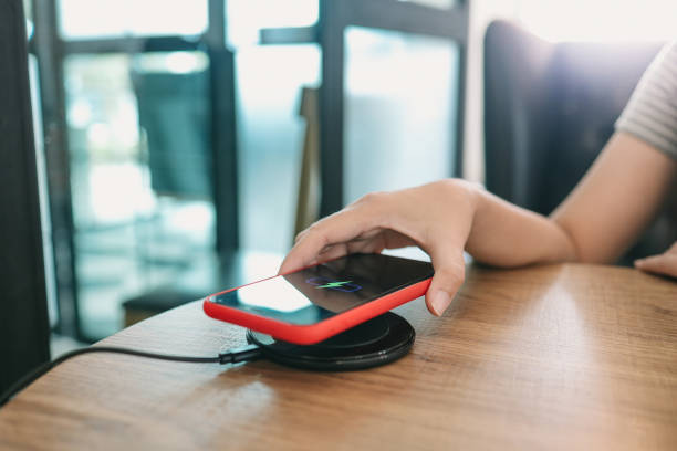 istock Charging mobile phone battery with wireless charging device in the table. Smartphone charging on a charging pad. Mobile phone near wireless charger Modern lifestyle concept. 1304689320