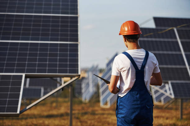 istock Stands with notepad. Male worker in blue uniform outdoors with solar batteries at sunny day 1304691588