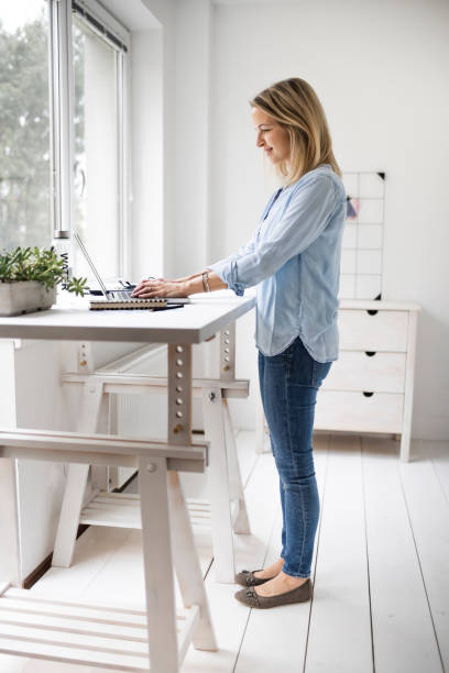 Businesswoman working at ergonomic standing workstation. Businesswoman working at ergonomic standing workstation. standing desk photos stock pictures, royalty-free photos & images