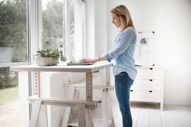 Businesswoman working at ergonomic standing workstation.