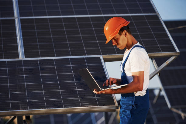 istock Using laptop. Male worker in blue uniform outdoors with solar batteries at sunny day 1304693681