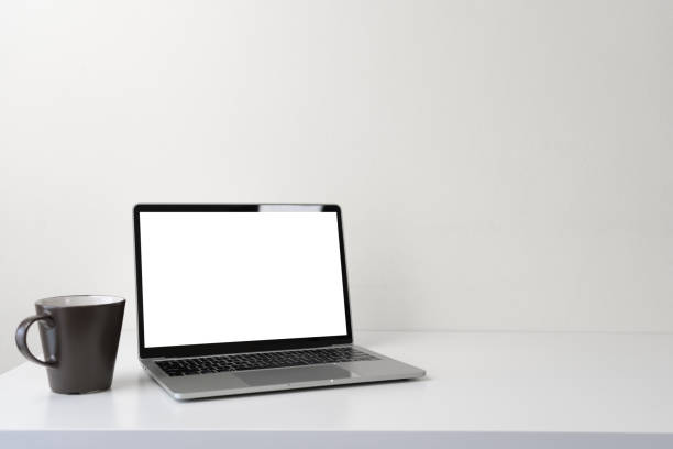 istock Modern contemporary workspace with blank screen laptop computer and coffee cup on office desk table on white background for copy space. Home office workplace concept. 1304694006