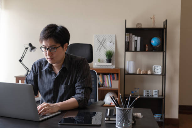 istock Asian freelancer business man working at home using laptop computer at workspace office desk in living room. Remote work from home. 1304694077