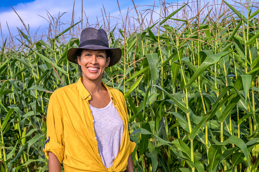 Portrait of smiling mature female farmer standing in maize field.
