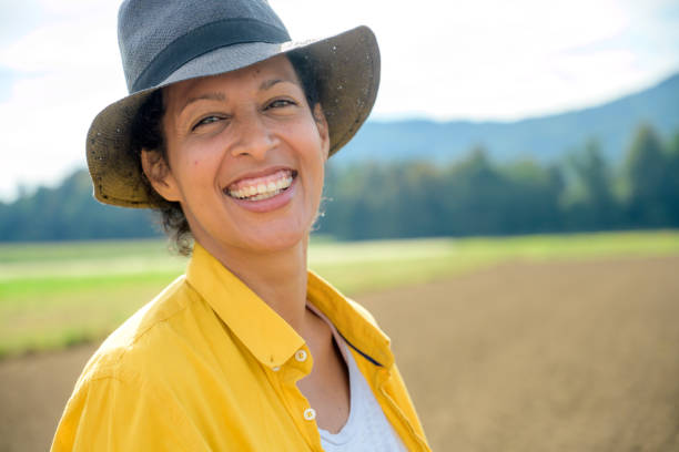 Portrait of smiling female farmer standing in field.