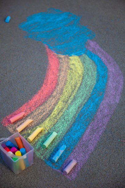 istock A rainbow painted on the asphalt with multicolored large crayons. Chalk and a bucket of crayons. LGBT symbol 1304697697