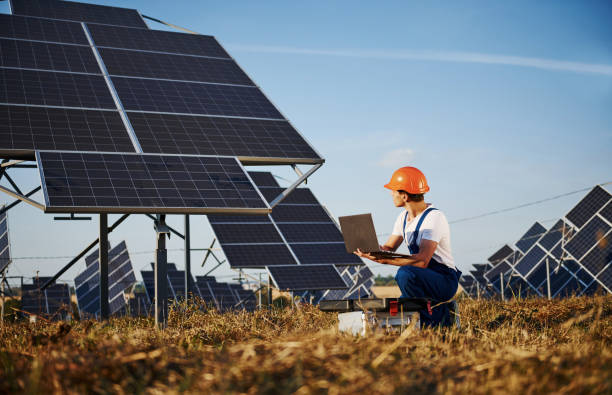 istock Using laptop. Male worker in blue uniform outdoors with solar batteries at sunny day 1304697807