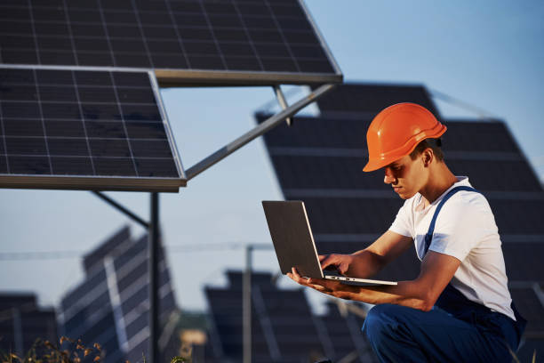 istock Using laptop. Male worker in blue uniform outdoors with solar batteries at sunny day 1304699088