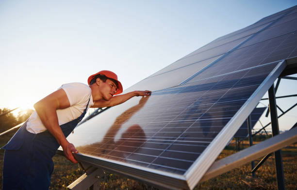istock Beautiful sunlight. Male worker in blue uniform outdoors with solar batteries 1304699090