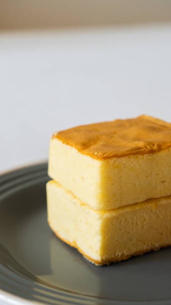 istock Square fluffy egg sponge cake on a black plate, breakfast pastry, vertical image 1304701689
