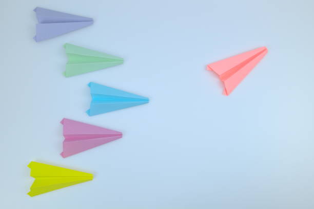 istock Pink paper airplane flying in multicolor paper airplanes. 1304702602