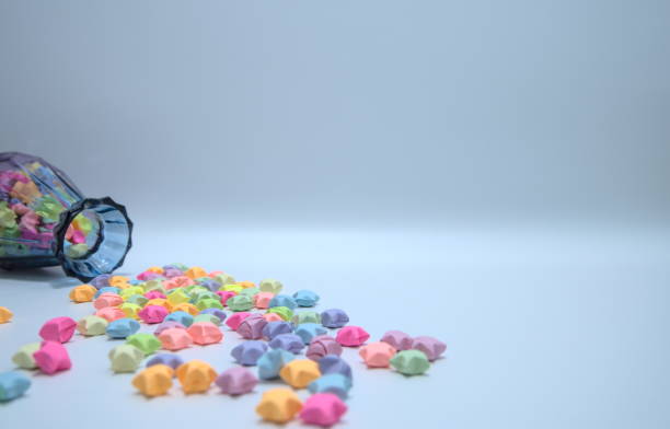istock Multicolor paper stars scattered on desktop from a glass bottle. Copy space 1304702616