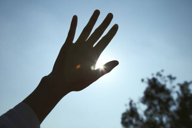 istock Backlight cropped hand covering sun. Low-angle view. Lens flare 1304702618