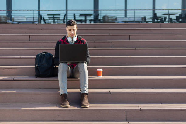 istock Young man sitting on stairs and using laptop 1304704439