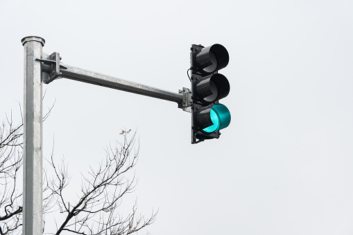 Traffic light on green, with blue sky and clouds on the background. Copy space