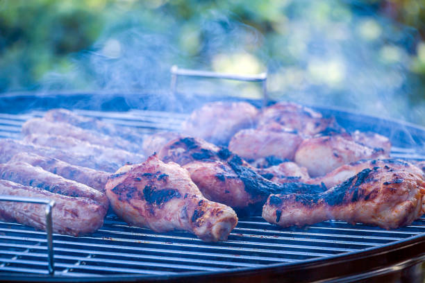 istock Burnt, charred chicken. Process cooking chicken drumstick and sausages on barbecue grill outdoors. Picnic, eating outdoors. Metal barbecue grill (brazier). 1304706093