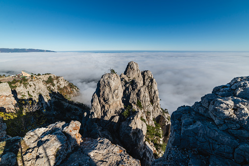 Rocky mountain range in the daytime in the fog above the clouds. Battlements of Mount Ai-Petri, Yalta, southern coast of Crimea