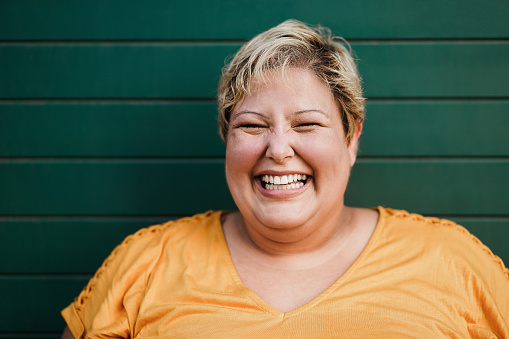 Retrato de una mujer curvilínea sonriendo en la cámara al aire libre con fondo verde - Concéntrate en la cara photo