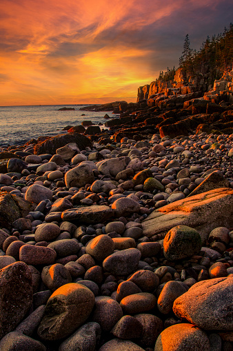 Early morning on a beach covered with round stones at Acadia National Park, Maine.  Otter Cliffs can be seen in the background lit by the morning light.