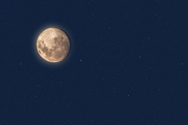 istock Full moon at dusk glowing against blue starry sky dark background 1304713982