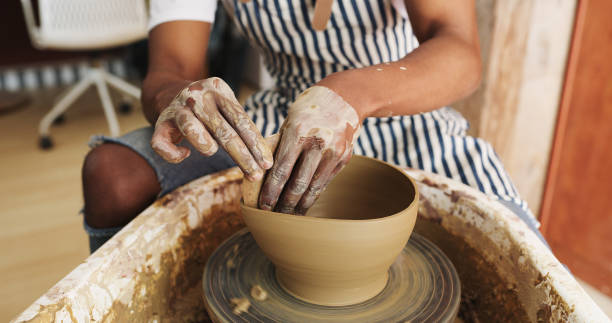 From plain old mud to an amazing bowl Shot of an unrecognisable man working with clay in a pottery studio pottery making stock pictures, royalty-free photos & images