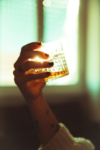 Women hand holding an alcoholic drink backlit sun
Analogic film like