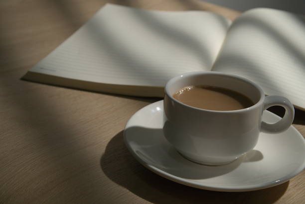 istock A cup of coffee and open blank notebook on the desk, desktop in the evening 1304716677