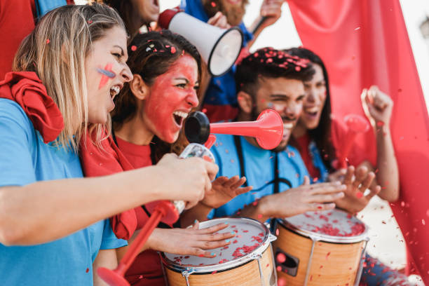 istock Crazy sport fans playing drums and screaming while supporting their team - Focus on left woman face 1304719556