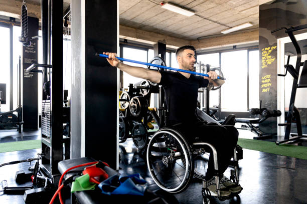 hombre de mediana edad en silla de ruedas haciendo ejercicio en la foto de archivo del gimnasio - parálisis fotografías e imágenes de stock