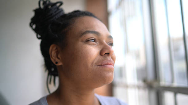 istock Young woman looking through the window at home 1304721853