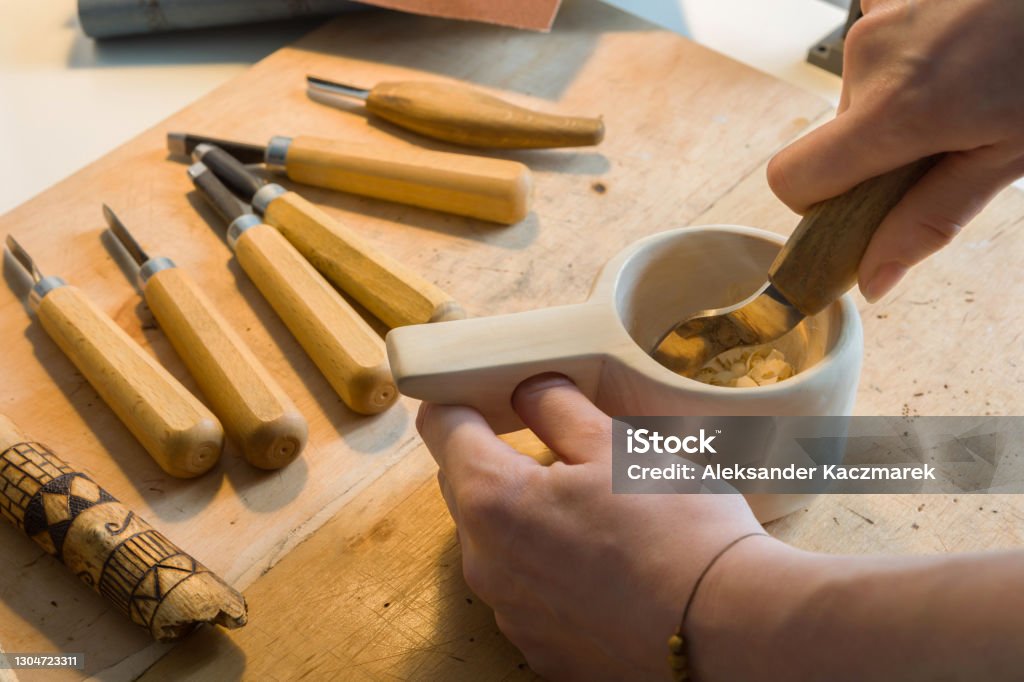 Close-up of female hands carving wooden mug kuksa Female hands carving wooden mug kuksa with curved chisel. Art Stock Photo