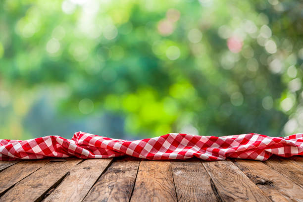 istock Empty rustic picnic table with crumpled gingham cloth against defocused nature background 1304724606
