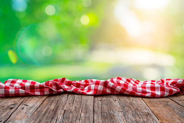 istock Empty rustic picnic table with crumpled gingham cloth against defocused nature background 1304724610