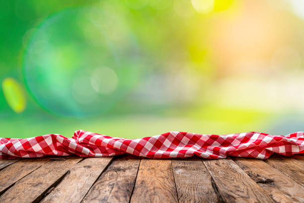 istock Empty rustic picnic table with crumpled gingham cloth against defocused nature background 1304724633