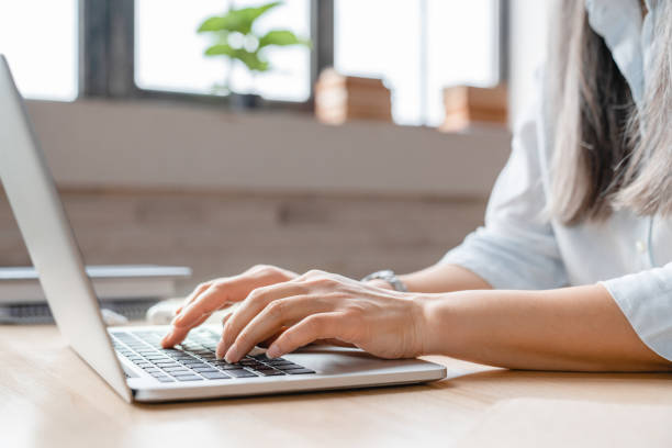 immagine ravvicinata delle mani della donna che digitano sul laptop alla scrivania - women typing human hand computer key foto e immagini stock