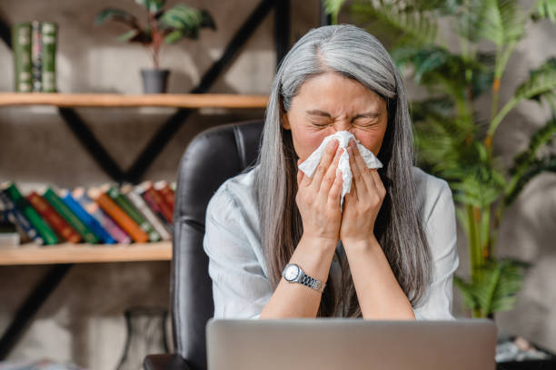 istock Sick mature white woman sneezing at work place in office 1304725667