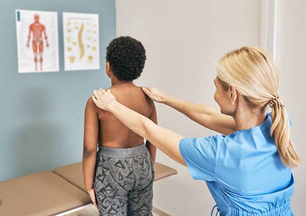 男性の子供に背骨を調べるオステオパス。小児に対する健康診断、脊柱側弯症、小児への脊柱症 - scoliosis ストックフォトと画像